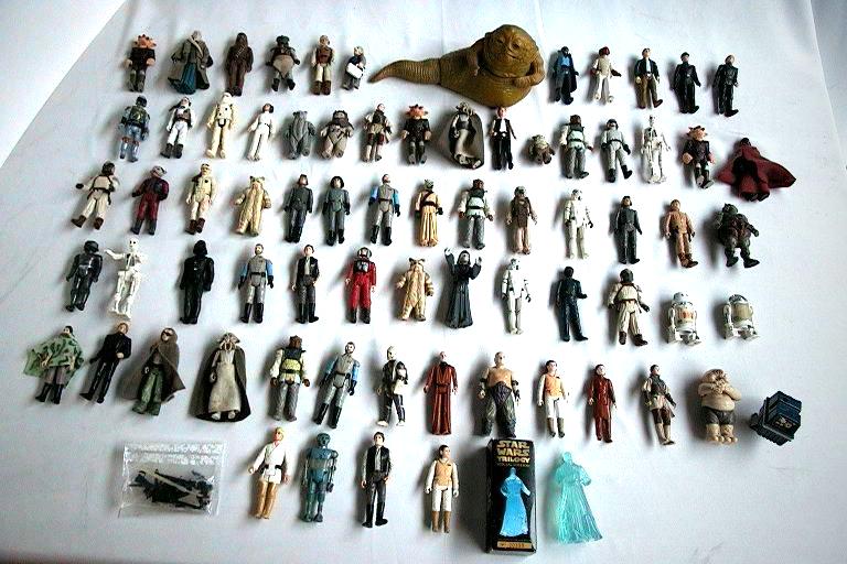 Rows of vintage Star Wars action figures laid out on a white surface, with a Jabba figure at the top